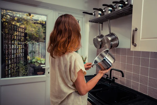 Young woman in kitchen cooking with saucepan