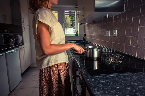 Young woman in kitchen cooking with saucepan