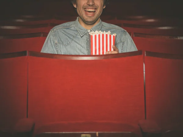 Happy young man watching movie in cinema