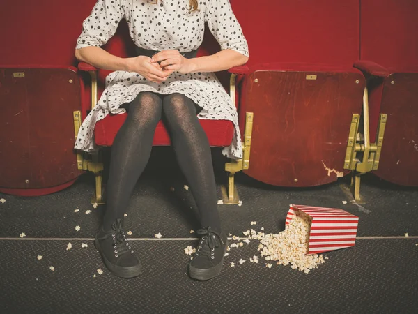 Woman in theater with popcorn on the floor