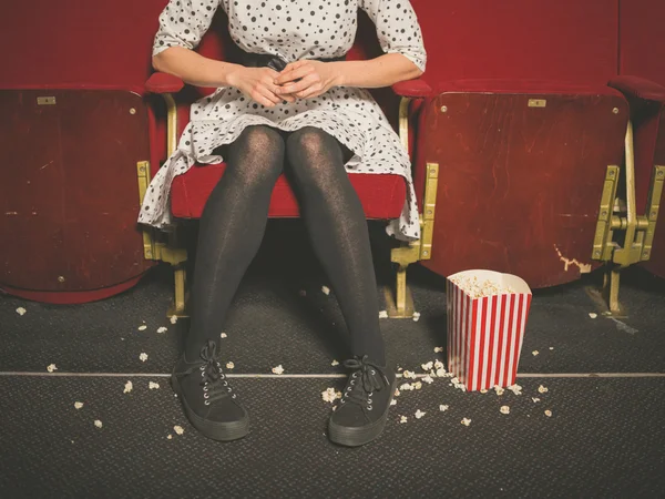 Woman in theater with popcorn on floor