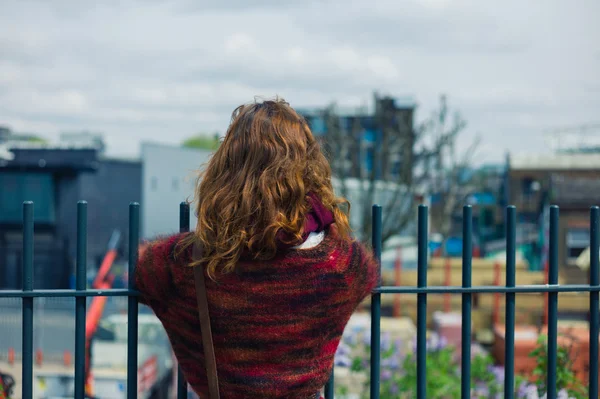 Woman standing by fence at builders yard