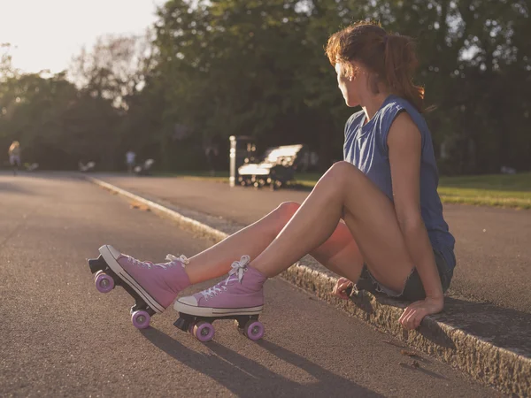 Young woman sitting in park with roller skates