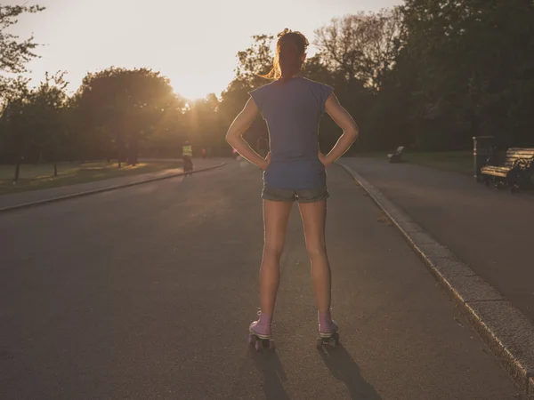 Young woman wearing roller skates in park at sunset