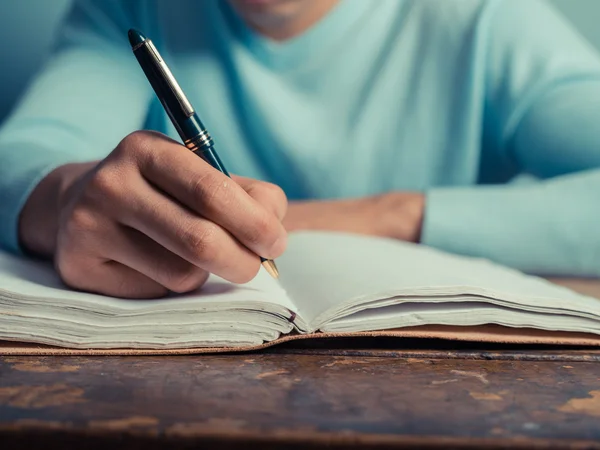 Young man writing in notebook
