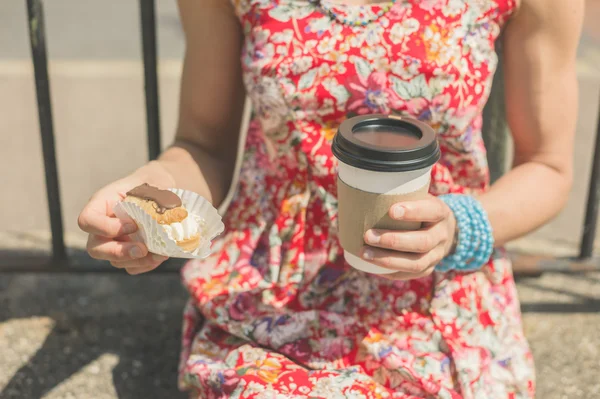 Young woman with coffee and cake outside