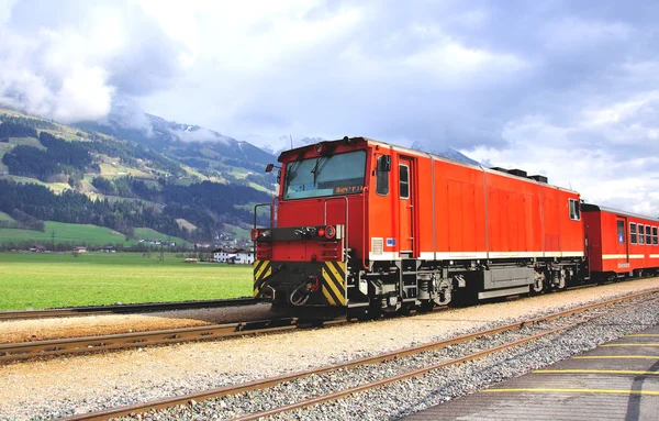 Old fashioned red train goes through the austrian Alps