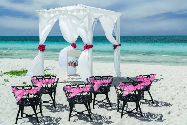 Amazing gorgeous inviting view of wedding decorated gazebo with old vintage black metal chairs on the beach