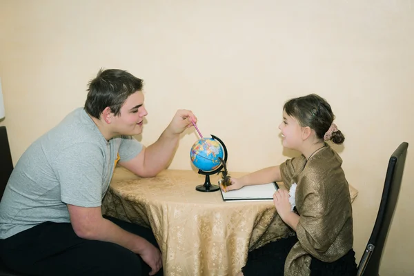 Boy and little beautiful girl sitting and having fun with exploring and learning the world globe