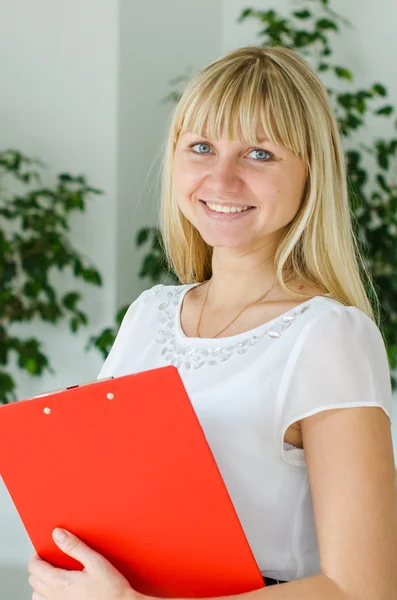 Young woman with red folder in his hands is smiling and exudes confidence