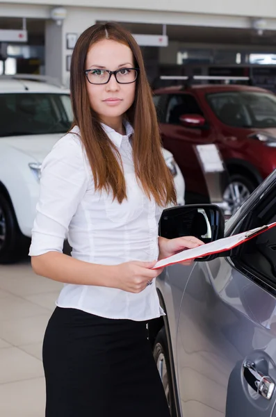 Young woman standing in the showroom with a red folder