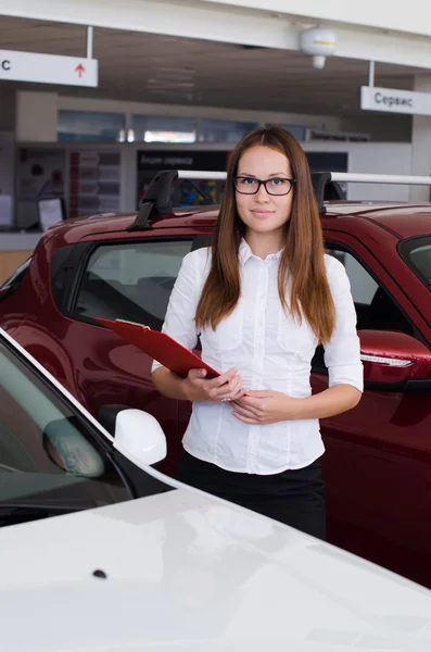 Young woman standing in the showroom with a red folder