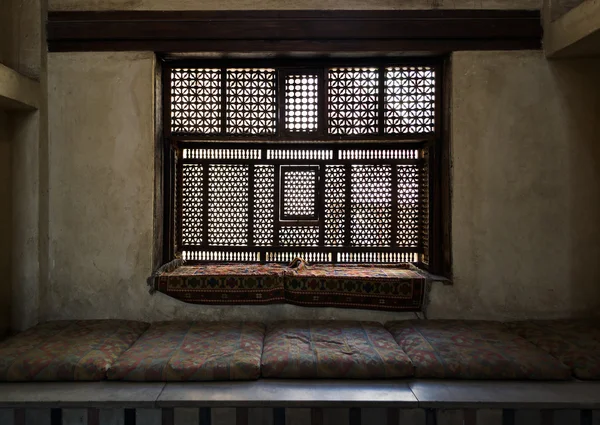 Aged interleaved wooden window (Mashrabiya) and a built-in couch