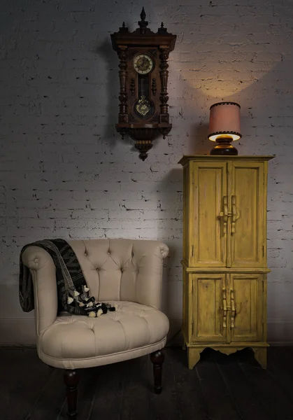 Beige armchair, yellow cupboard, pendulum clock and illuminated