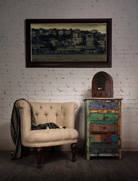 Vintage beige armchair, colorful cupboard, old radio and hanged painting
