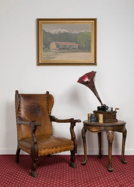 Leather armchair, vintage round table and painting on red carpet