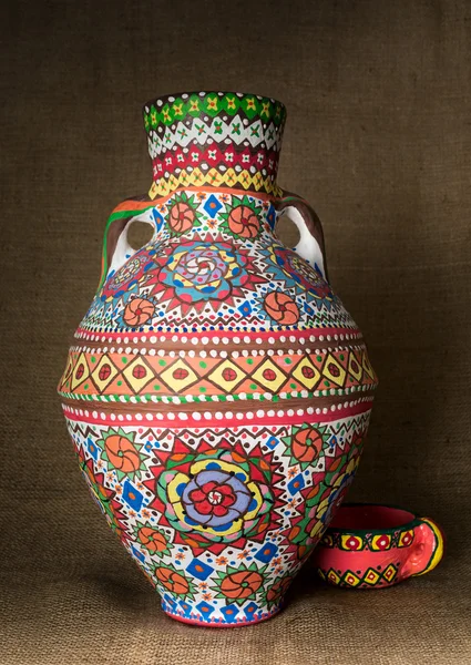 Colorful Egyptian handcrafted artistic ornate pottery jar on sackcloth background