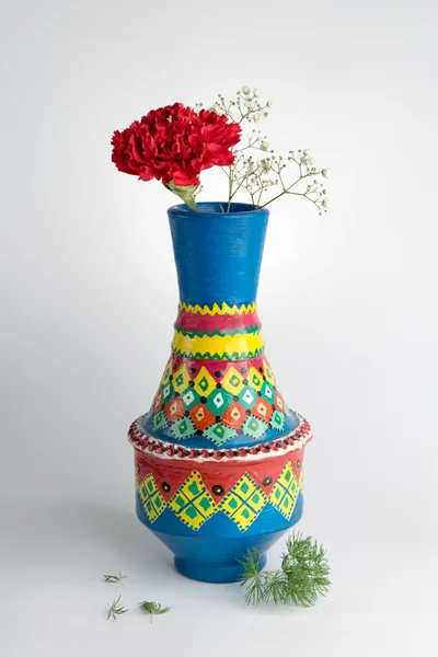 Colorful pottery vase with red flower on white background