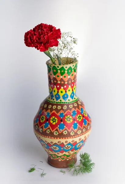 Colorful pottery vase with red flower on white background