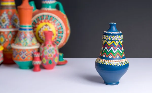 Decorated colorful pottery vase on background of blurred colorful vases