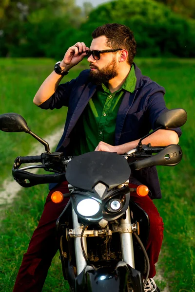 View of a man with a motorcycle on a dirt road among fields.