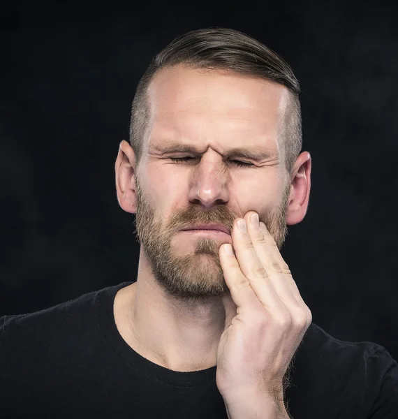 Toothache. Portrait of a man with face closed by hand.