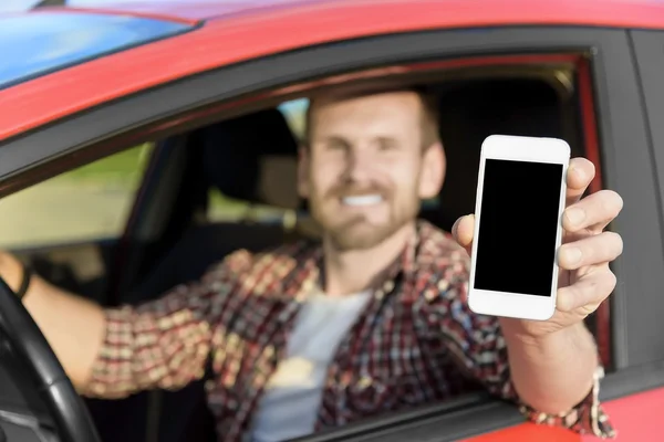 Man in car driving showing smart phone.