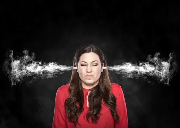 Smoke from the ears of a woman over dark background.