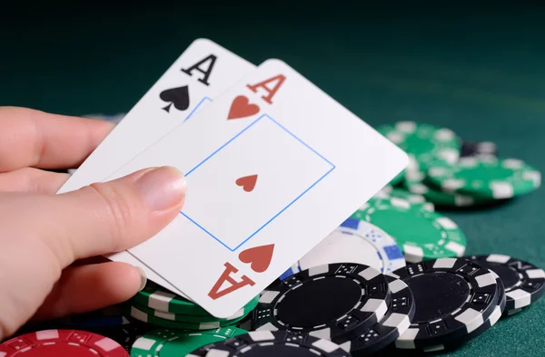 Casino chips and pair of aces in a womans hand. Poker game concept