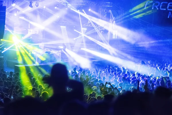 Silhouettes of concert crowd in front of bright stage lights