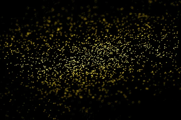 Abstract Golden glitter texture on a black background. Defocused