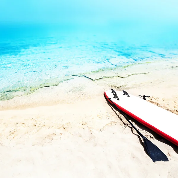 Holiday beach sunny seascape with surf board, sand and ocean. Su