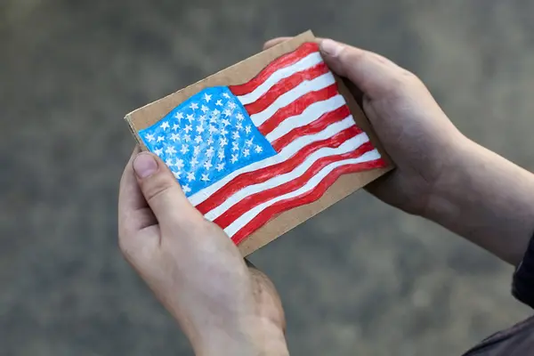 Homeless boy holding a American Flag painted on paper