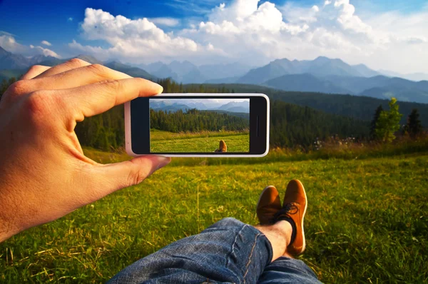 Man taking a photo of a landscape with his phone - point of view