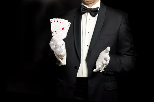 Elegant man in tuxedo holding 4 aces in hand