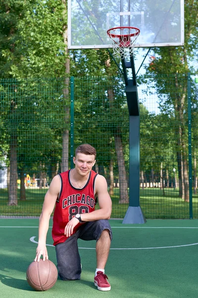 B-boy sitting on basketball field with ball