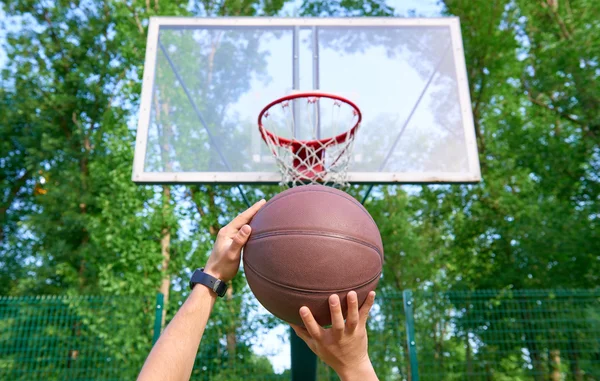 Hands throwing basketball ball into basket