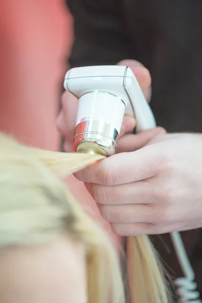 Hair treatment. hair testing. man's hand with the device for testing fiber optic links