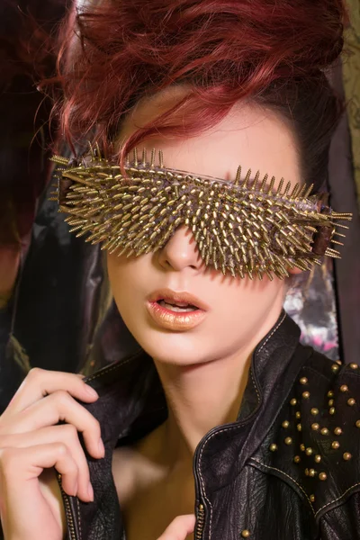 Young girl with red hair wearing glasses with gold spikes