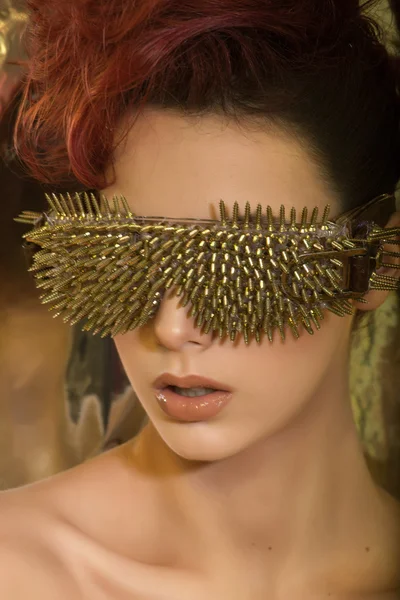 \young girl with red hair wearing glasses with gold spikes in th