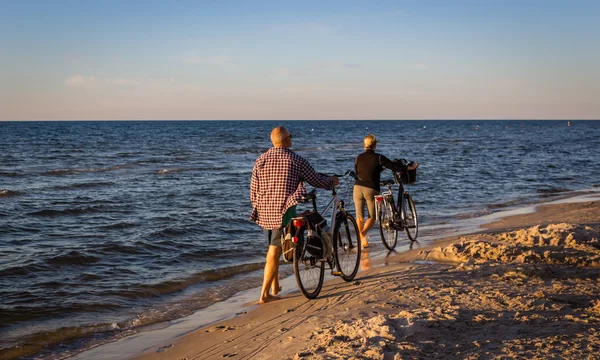Elderly couple with bicycles walking by sea