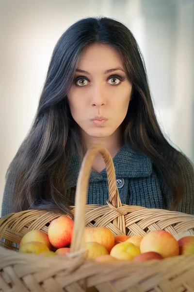 Surprised woman with a basket of ripe apples