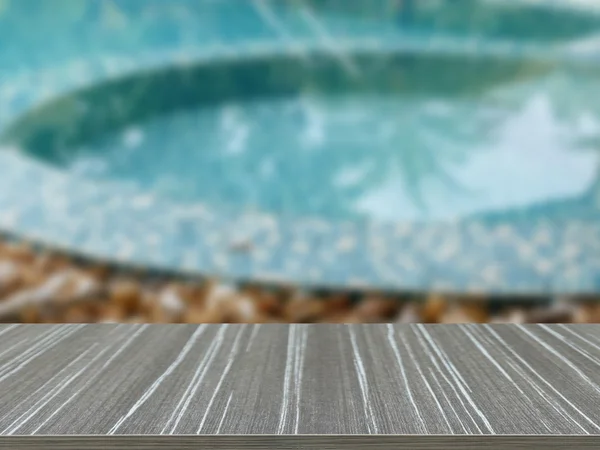 Empty wooden table with stone on the edge of the swimming pool b