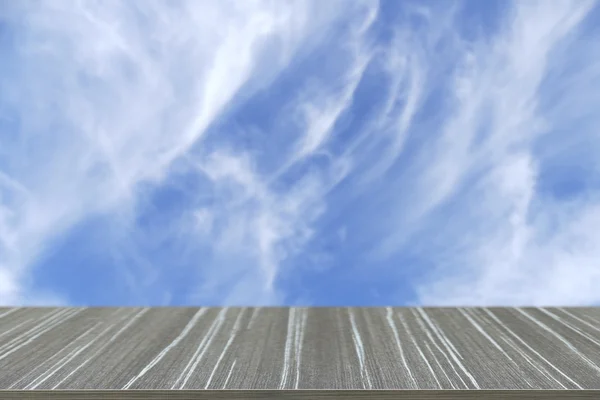 Empty wooden table with cloudscape and blue sky blur background