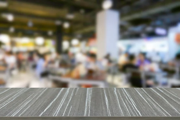 Empty wooden table with people eating food in food court blur ba
