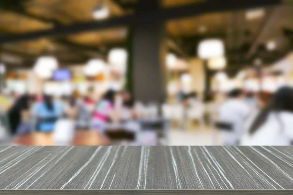 Empty wooden table with people eating food in food court blur ba