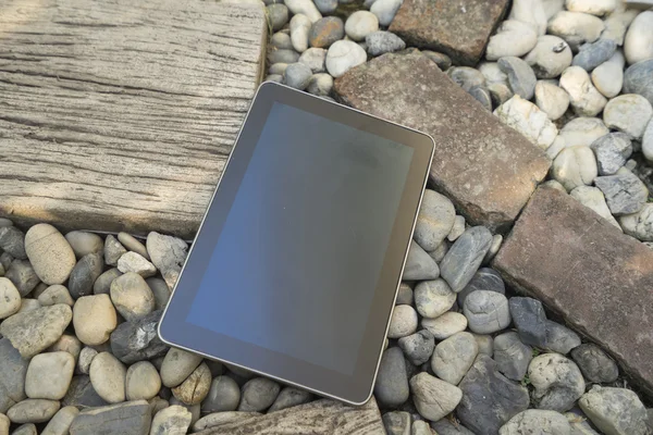 Digital tablet device on stone and wooden walkway