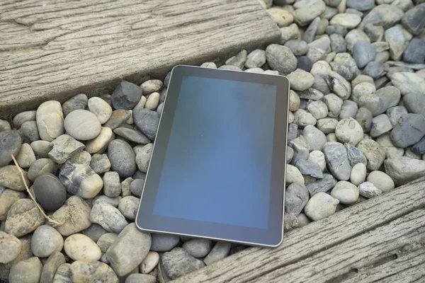 Digital tablet device on stone and wooden walkway