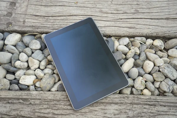Digital tablet device on stone and wooden walkway