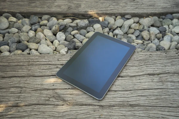 Digital tablet device on stone and wooden walkway